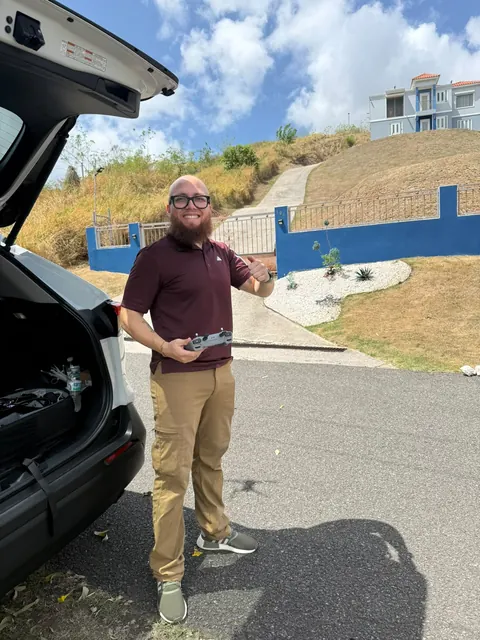 Justin, de Ground Sky Studios, sonriendo con el control del dron en la mano junto a su carro